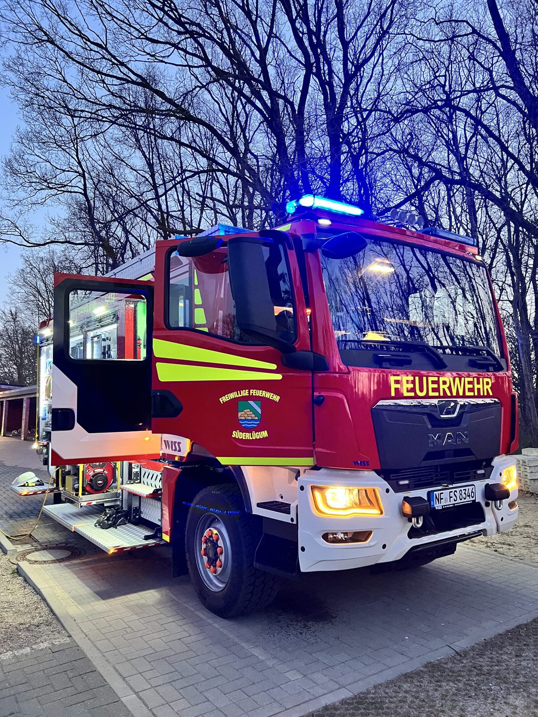 Einsatzfahrzeug der Feuerwehr Süderlügum in der Abenddämmerung mit eingeschaltetem Blaulicht